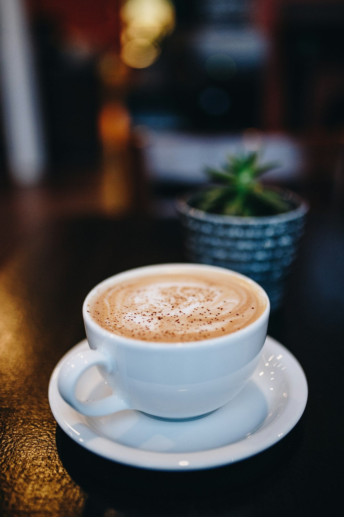 Cappuccino in a white stoneware cup and saucer on a wooden table