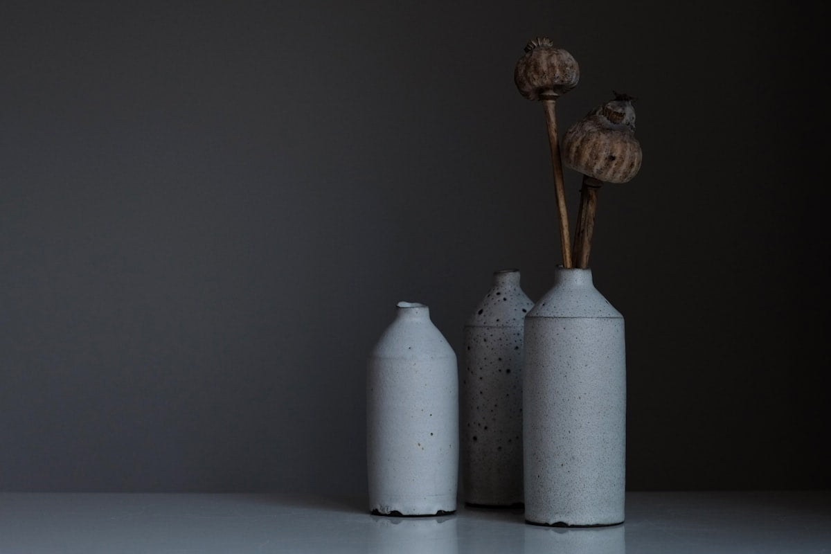 Matte grey stoneware bottle vases holding dried seed pods