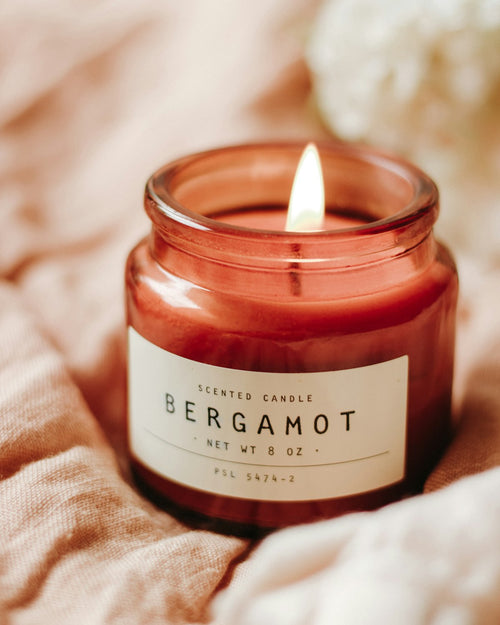 Bergamot soy candle in an amber glass jar on washed linen