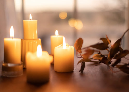 Cluster of lit ivory pillar candles by a window at dusk