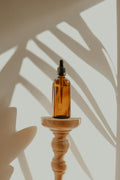 Amber glass dropper bottle of fragrance oil in dappled sunlight