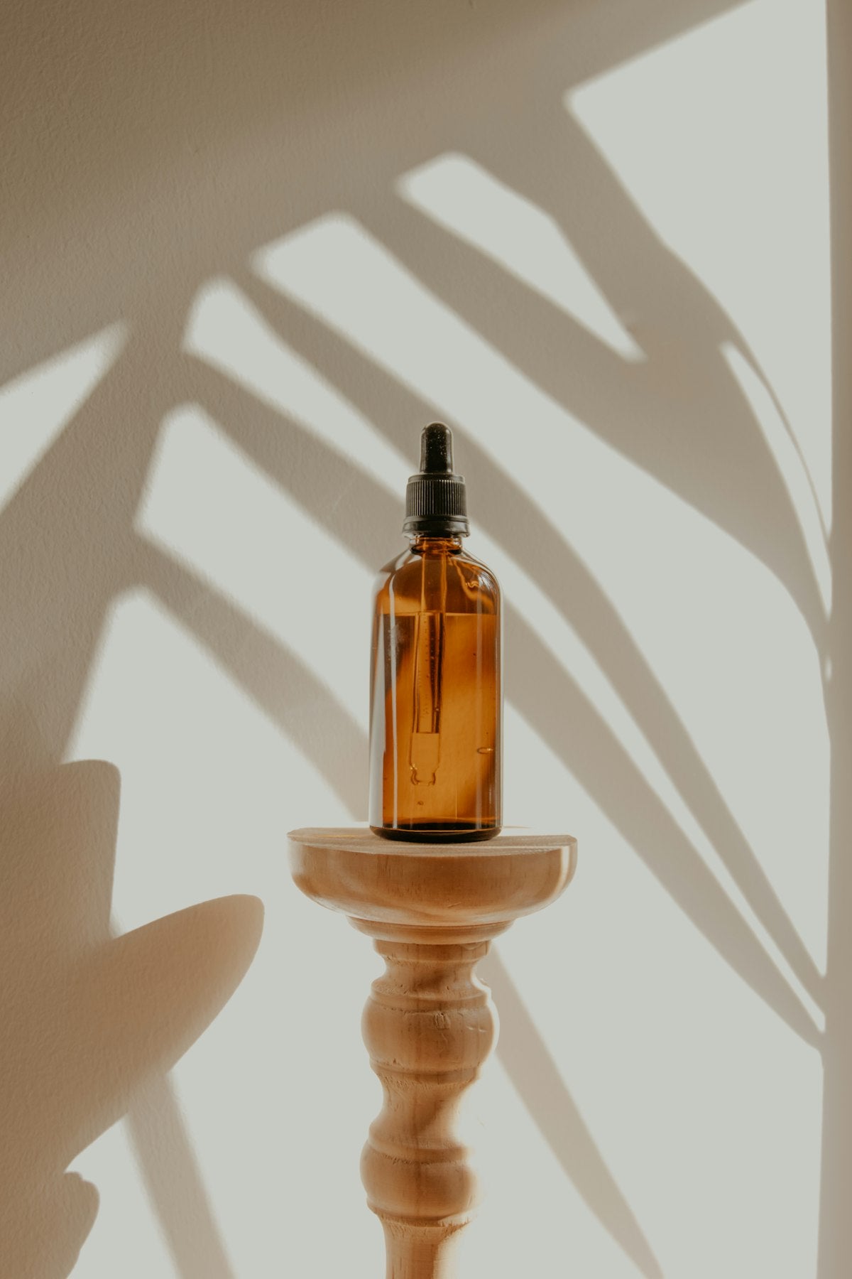 Amber glass dropper bottle of fragrance oil in dappled sunlight