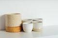 Speckled stoneware tumblers and crock on a white shelf