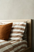 Rust and ivory striped linen pillowcases on an oak bed frame