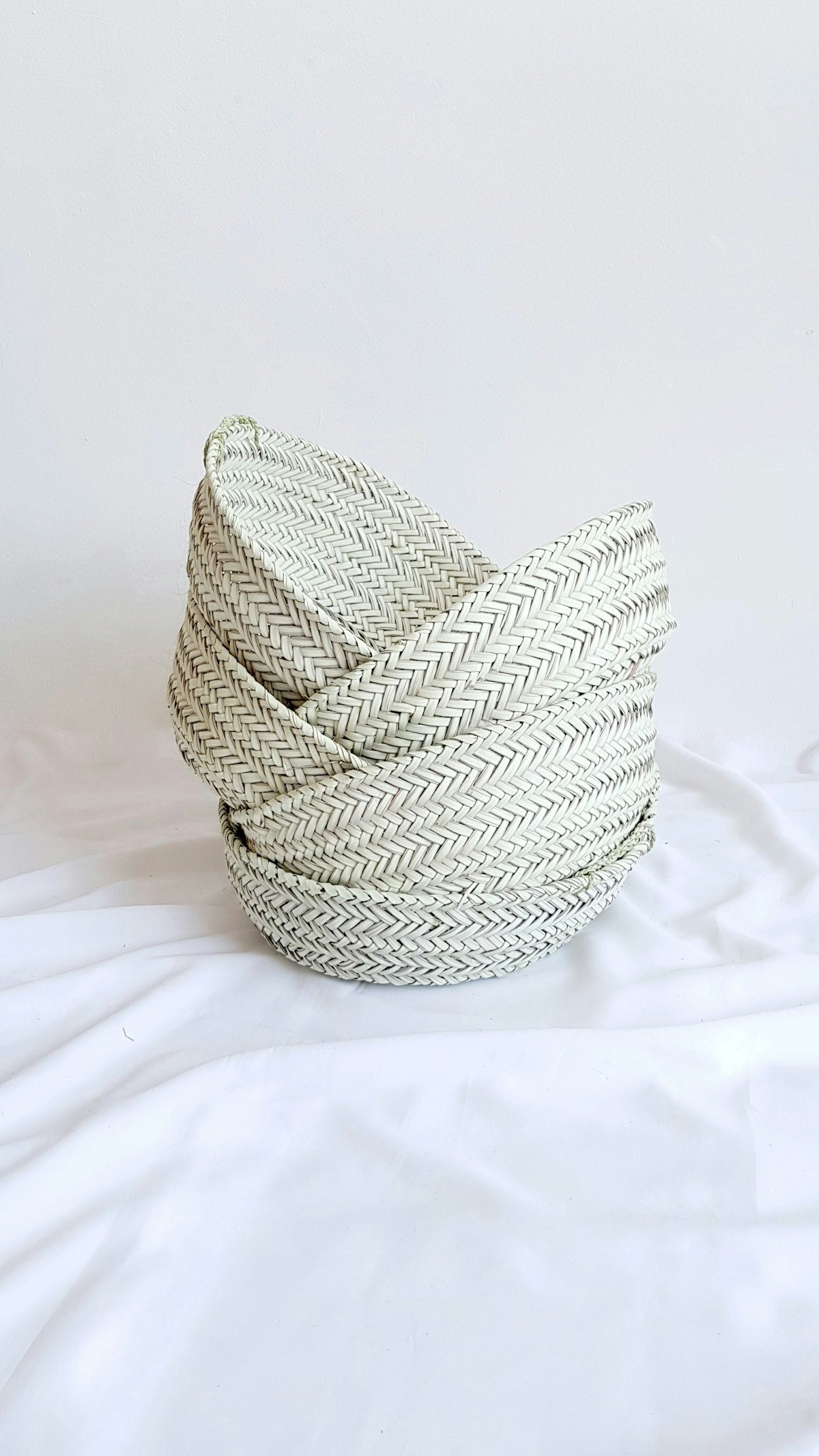Stack of handwoven palm baskets in sage and natural weave